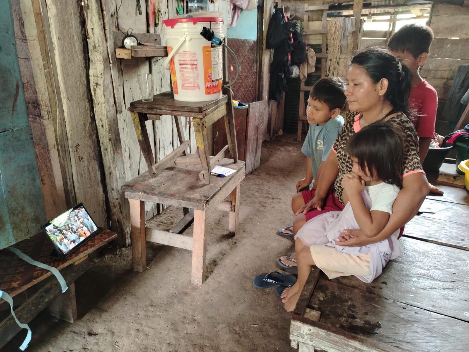 A family in a remote home watching a film on a tablet.
