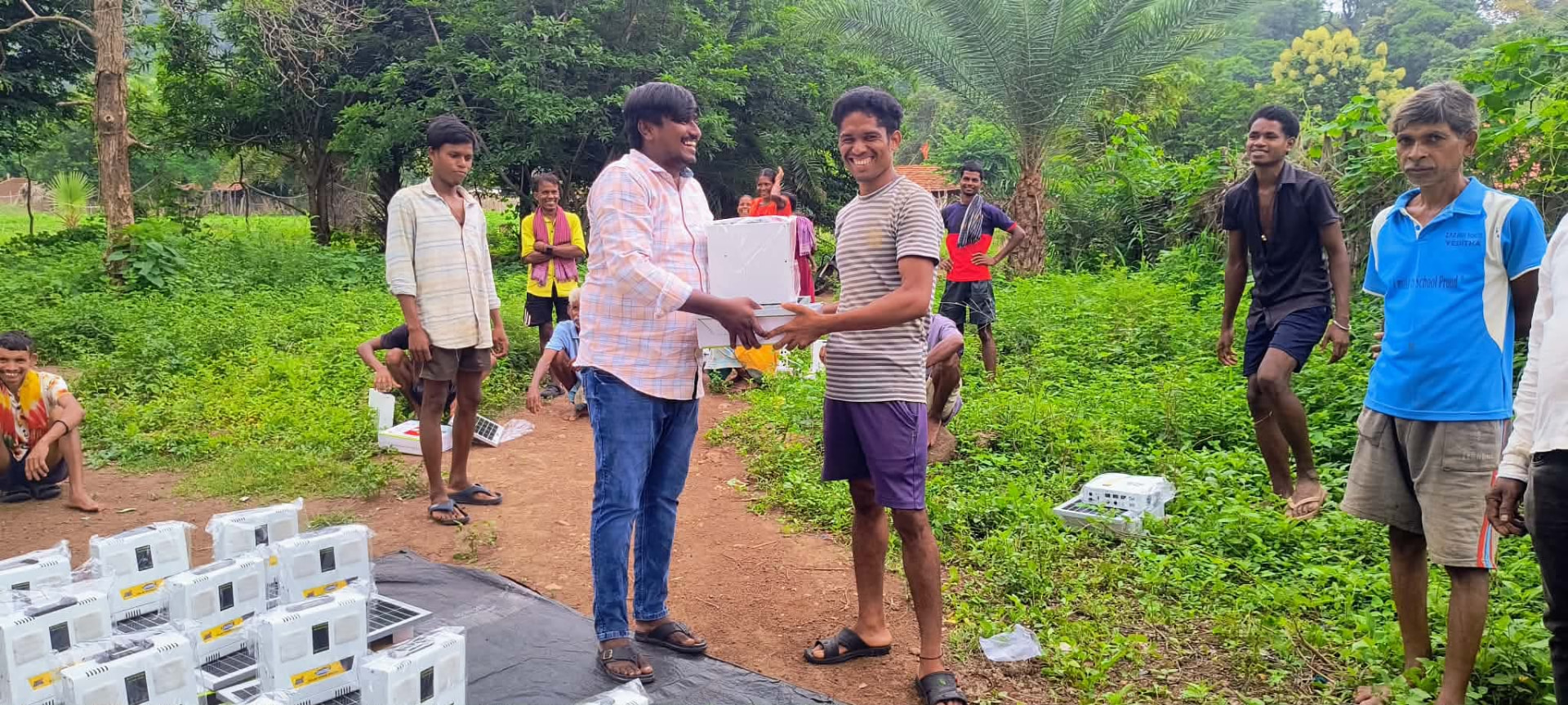 Ministry worker handing a solar light kit to a villager as neighbors gather.