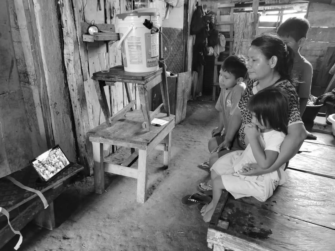 A family in a remote home watching a film on a tablet.